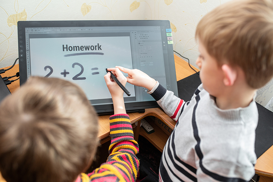 Image of young boys doing homework on a large touchscreen. 