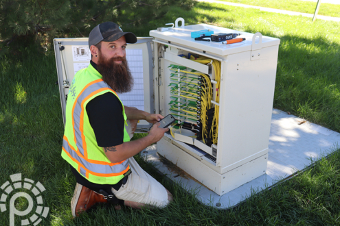 A Pulse field technician working at a fiber cable box.