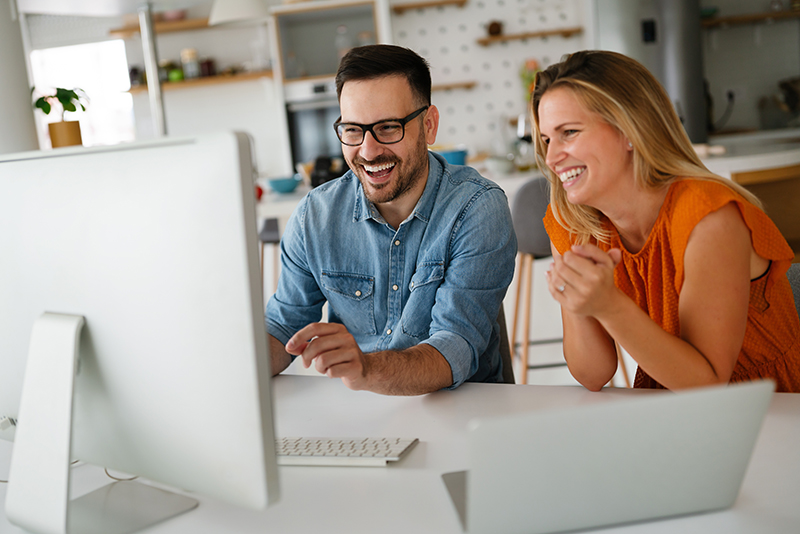 Image of two people looking at a computer screen and smiling