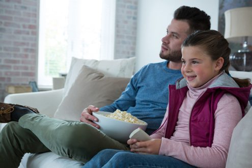Image of father and daughter on couch watching TV
