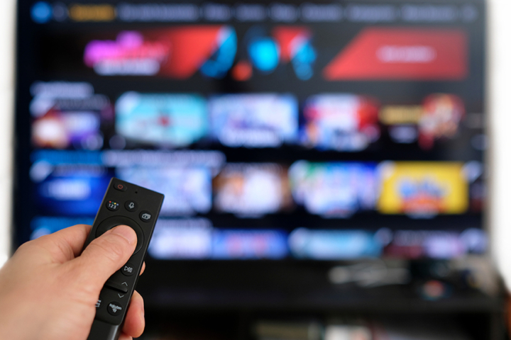 Image of a hand holding a remote pointed at a TV