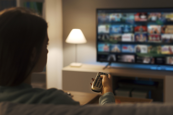 Photograph of woman watching TV from her couch